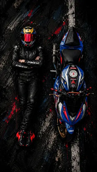 검은색 Dainese 가죽 수트와 헬멧을 쓴 사람이 어두운 도로에서 파란색과 빨간색 Yamaha 오토바이 옆에 서 있습니다.