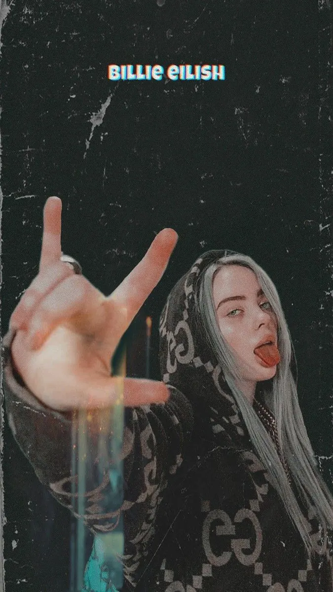 Uzun açık renkli saçlı Billie Eilish, desenli siyah bir kapüşonlu giyiyor ve dilini çıkararak rock el işareti yapıyor.