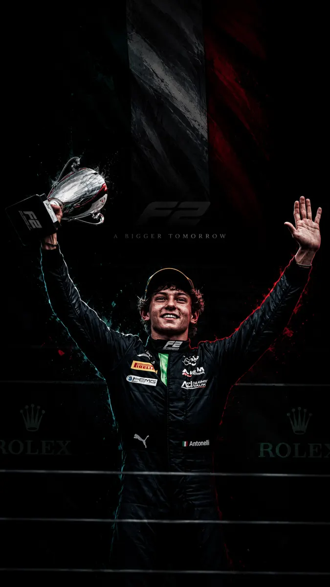 Kimi Antonelli sonriendo y sosteniendo un trofeo de F2 sobre su cabeza mientras viste un traje de carreras negro en un podio.