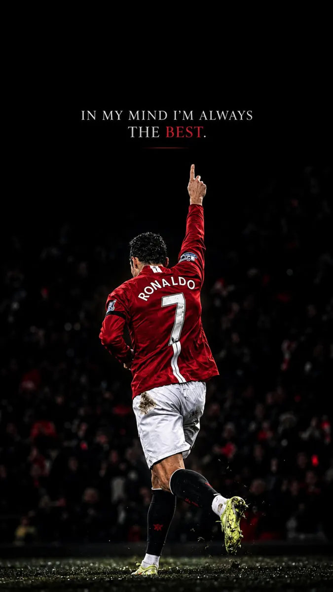 Cristiano Ronaldo visto de espaldas vistiendo una camiseta roja del Manchester United con el número 7, señalando con el dedo hacia arriba en un campo oscuro.